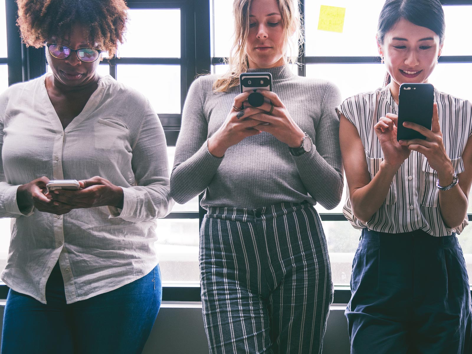 Three women looking at their smart phones.