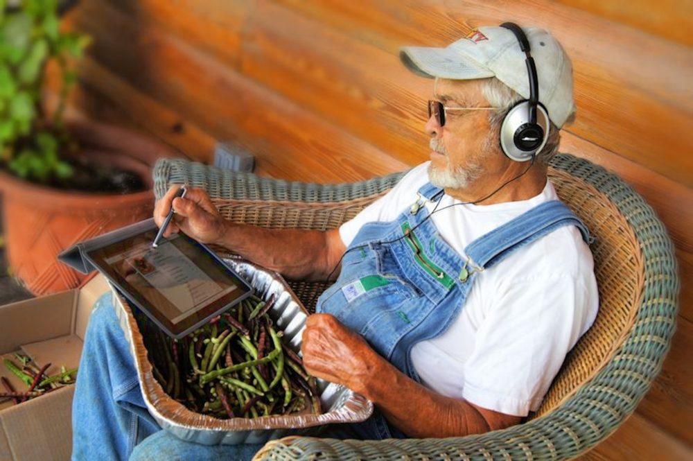 A farmer listens to audio with headphones while doing work.